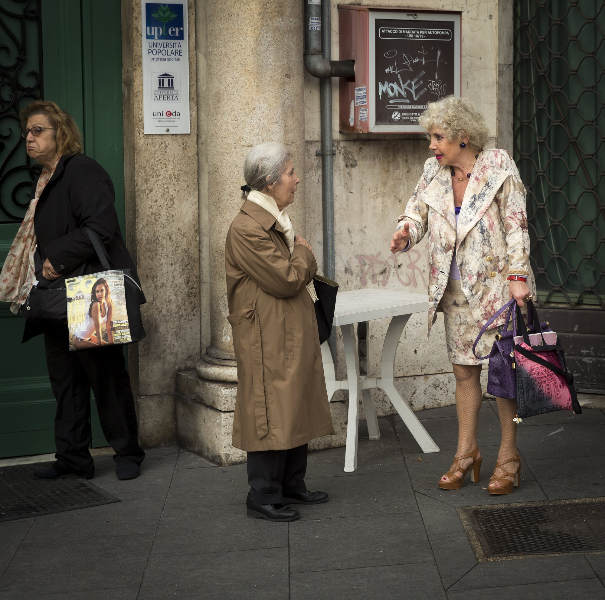 Rome. I first saw these two women deep in conversation which would have made for a nice shot, but then the third woman appeared carrying a shopping bag with the picture of a young woman and suddenly there were a couple of more layers to the shot. Canon 5D MIII with 24-70mm lens set to 70mm, 1/350 sec. ISO 800