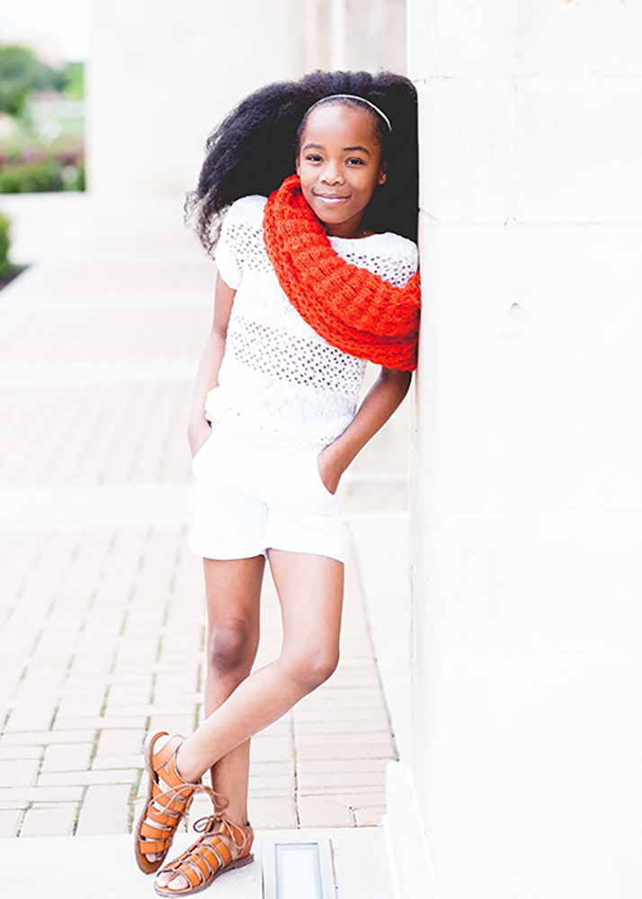 little girl posing naturally while leaning on a wall